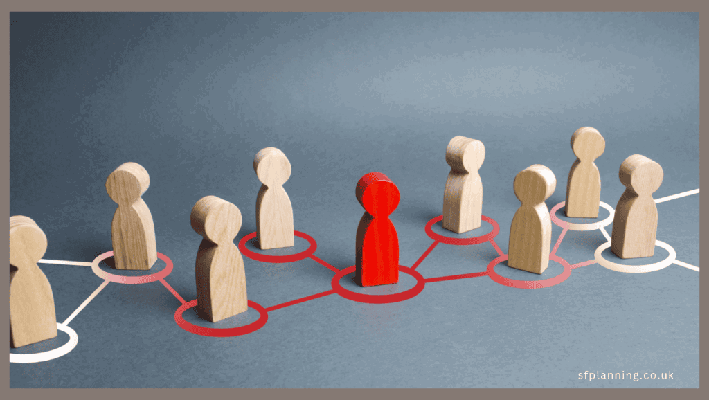 Nine wooden figures, connected by lines. Eight of the figures are natural wood, while the centre figure is coloured bright red. The lines connecting the figures are white on the outermost figures, with a gradient to bright red where they meet the central figure. Illustrating the bottleneck of Development Management